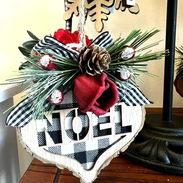 Buffalo-check Noel ornament with pine and a red bow