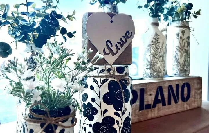Hand-decorated bottles, greenery and a wooden Plano sign in the shop window